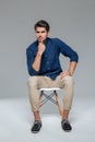 Pensive attractive casual young man sitting on chair