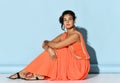 Pensive attractive woman with greek appearance wearing traditional ethnic dress decoration jewelry sitting on floor studio shot