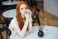 Pensive attractive young woman sitting at the table in cafe