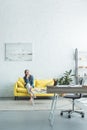 pensive barefoot girl sitting on sofa and looking away