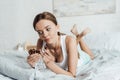 Barefoot young woman holding chocolate with nuts in bed