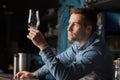 Pensive bartender looks at clean glass for beer, standing behind bar Royalty Free Stock Photo
