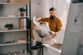 Pensive bearded adult male architect sitting near house model, holding blueprint and working on project Royalty Free Stock Photo