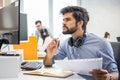 Pensive bearded business man with paper document and pen looking at computer screen and thinking of problem solution Royalty Free Stock Photo