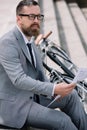 pensive bearded businessman reading newspaper on stairs Royalty Free Stock Photo