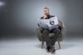 Pensive bearded businessman sitting in armchair and reading newspaper,