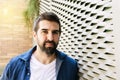 Pensive bearded male leaning on wall with hand on chin