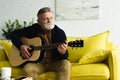 pensive bearded senior man playing guitar and looking away Royalty Free Stock Photo