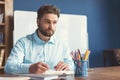Pensive bearded youthful guy doing employment test indoor