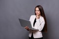 Pensive business woman with laptop on gray background Royalty Free Stock Photo