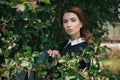 Pensive beautiful young girl in retro style dress standing in the garden near the fence. Closeup portrait. She is a teacher. Royalty Free Stock Photo