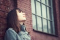 Pensive beautiful young girl standing near a brick wall Royalty Free Stock Photo