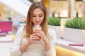 Pensive beautiful young woman drinking cocktail and thinking in cafe, looking down, hold cup with fresh baverage in hand, spend Royalty Free Stock Photo