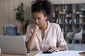 Pensive biracial woman manage budget on laptop at home