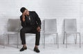 Pensive black guy in office wear waiting for job interview in company hall. Copy space