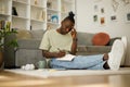 Pensive black teenager writing, taking notes, studying in a notebook while sitting on the floor at home Royalty Free Stock Photo