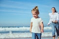 Pensive blonde child girl 2-3 years old in white t-shirt and casual denim, walking on the beach with her happy mother Royalty Free Stock Photo