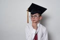 Pensive boy in academic hat and glasses on a white background. Kid education