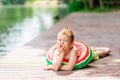 A pensive boy with a circle in the form of a watermelon in the summer lies on the shore of the lake, a child`s rest in the villag Royalty Free Stock Photo