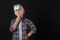 Pensive boy with question mark sticker on forehead against background. Space for text Royalty Free Stock Photo