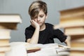 A pensive boy of 9-10 years old sits at a table with books. Gray background. Exams and learning difficulties Royalty Free Stock Photo