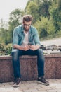 Pensive brutal young red bearded guy is typing a message outdoor Royalty Free Stock Photo