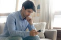 Pensive businessman holding cellphone thinking on offer received by email