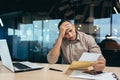 Pensive businessman inside office reading notification letter, man received envelope thinking about decision sitting at Royalty Free Stock Photo