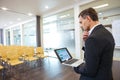 Pensive businessman with laptop standing in empty conference hall Royalty Free Stock Photo