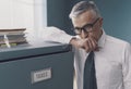 Pensive businessman leaning on a filing cabinet