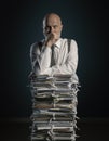 Pensive businessman leaning on a pile of paperwork