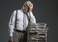 Pensive businessman leaning on a pile of paperwork