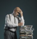 Pensive businessman leaning on a pile of paperwork