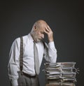 Pensive businessman leaning on a pile of paperwork