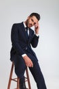 Pensive businessman in navy suit sitting on wooden stool Royalty Free Stock Photo