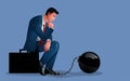 Pensive businessman seated upon a briefcase, shackled by the weight of an iron ball Royalty Free Stock Photo