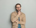 pensive casual man in beige jacket with glasses touching chin and thinking Royalty Free Stock Photo