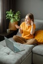 Pensive Caucasian beautiful woman work using laptop headphones remotely from home. Portrait of teenage girl student