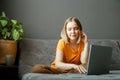 Pensive Caucasian beautiful woman work using laptop remotely from home. Portrait of teenage girl student thinking at Royalty Free Stock Photo