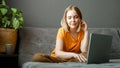 Pensive Caucasian beautiful woman work using laptop remotely from home. Portrait of teenage girl student thinking at home in Royalty Free Stock Photo