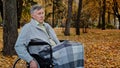 Pensive caucasian male mature man grandfather ride by wheelchair in autumn park sad serious senior older age person Royalty Free Stock Photo