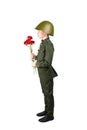 Pensive child in military uniform and helmet, stands sideways and holds cloves in hands