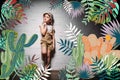 pensive child in safari costume standing at white wall