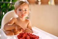 Pensive child sits on a high chair in front of a bowl of raspberries