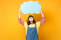 Pensive cute girl teenager in french beret, denim sundress looking up on blue empty blank Say cloud, speech bubble Royalty Free Stock Photo