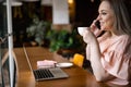 Pensive elegant plus size business woman drinking coffee working at cafe use laptop enjoying break Royalty Free Stock Photo