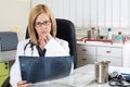 Pensive Female Doctor Looking at Patient's Lung X-ray in Consulting Room