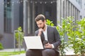 Pensive and focused male businessman working remotely at computer before making a difficult decision sitting near office before Royalty Free Stock Photo