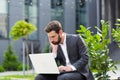 Pensive and focused male businessman working remotely at computer before making a difficult decision sitting near office before Royalty Free Stock Photo