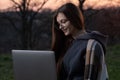 Pensive freelance professional working on laptop and thinking over project outdoors. Beautiful young woman in eyeglasses